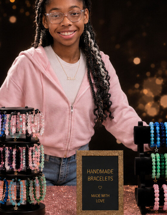 Maddison, the young founder of M by Maddison, smiling beside her handmade bracelets